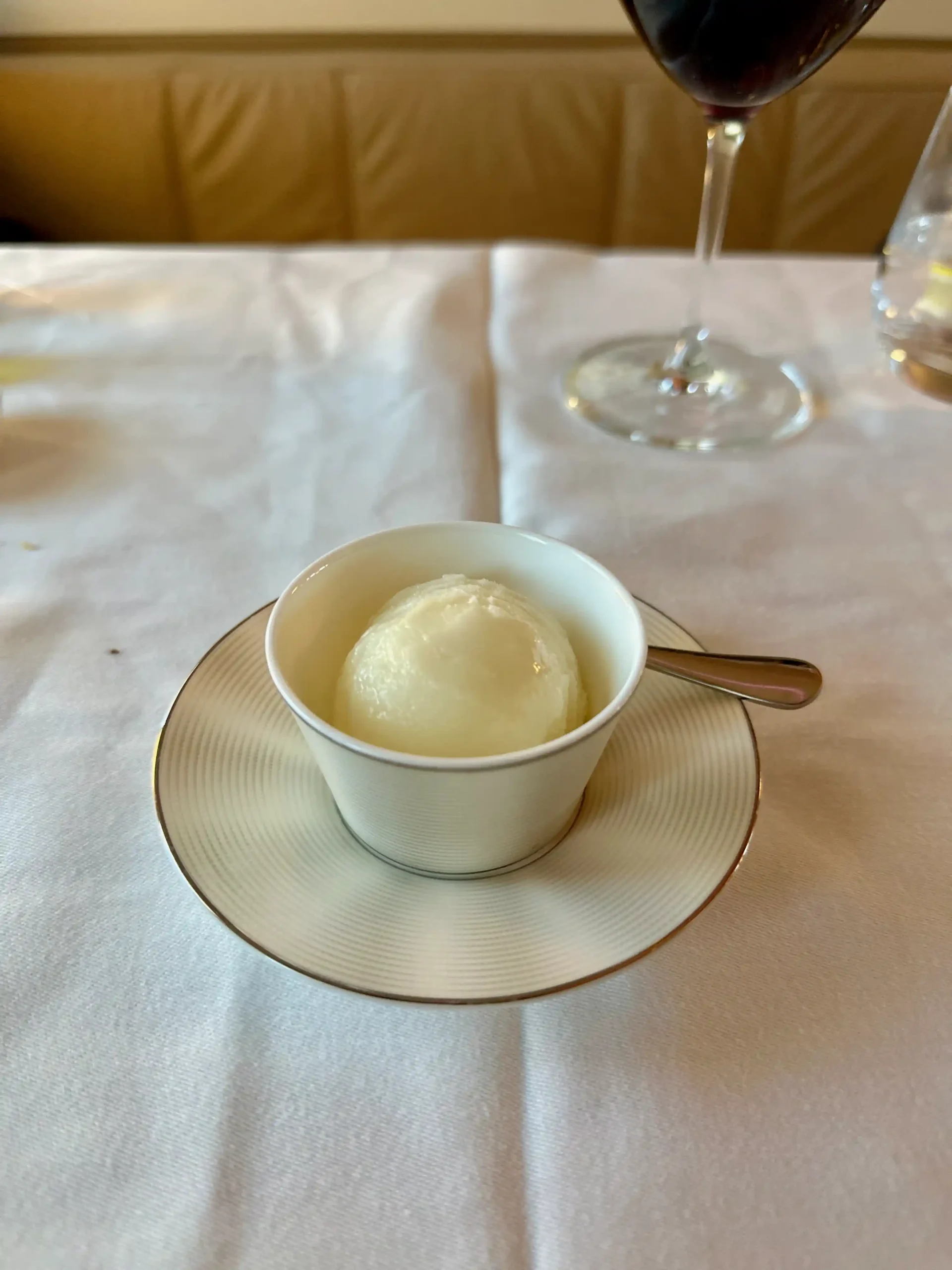 a white cup with a scoop of ice cream on a white tablecloth