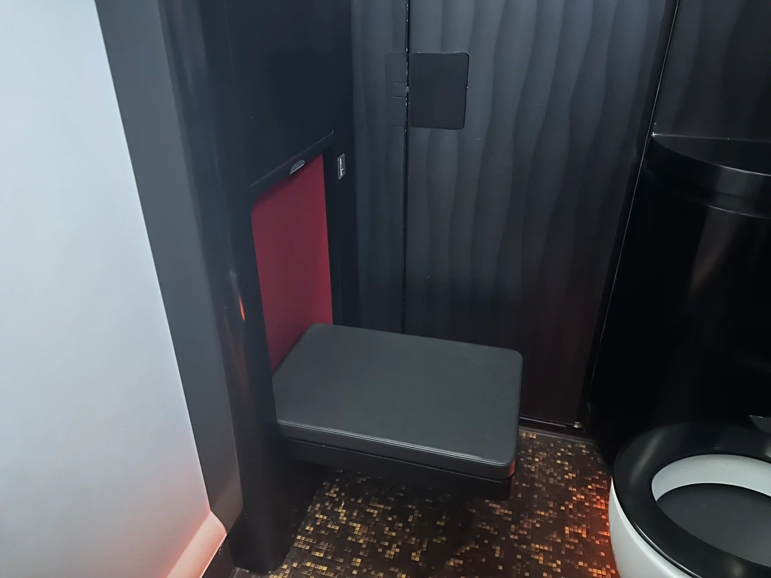 a black and red bathroom with a seat