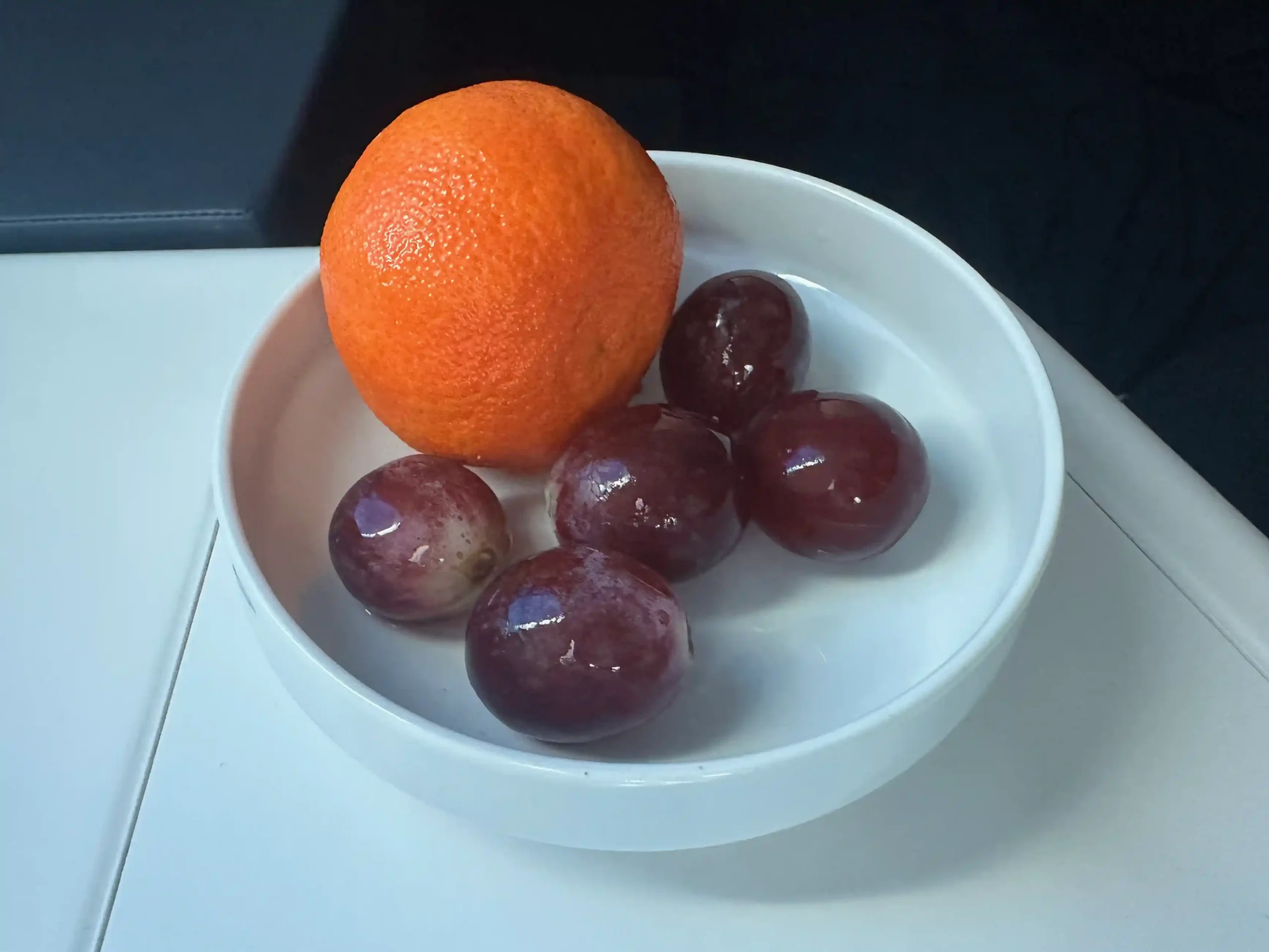 a bowl of grapes and an orange